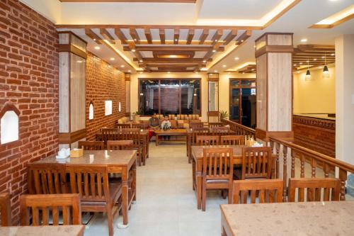 restauracja z drewnianymi stołami i krzesłami oraz ceglaną ścianą w obiekcie Madhuban Hotel w Katmandu