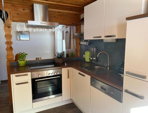 una cocina con armarios blancos y fregadero en Berghof am Schwand, en Hinterhornbach