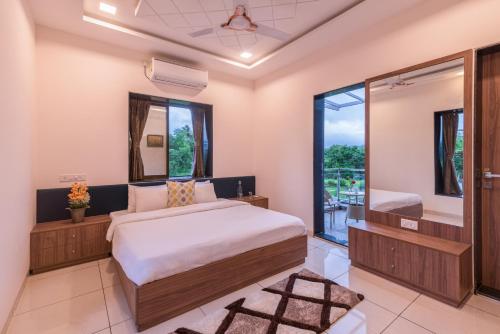 a bedroom with a bed and a mirror at SaffronStays Aster, plunge pool villa with garden, Lonavala in Lonavala