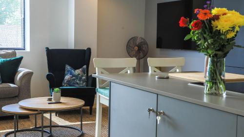a living room with a vase of flowers and chairs at Apartment Seven in Shrewsbury