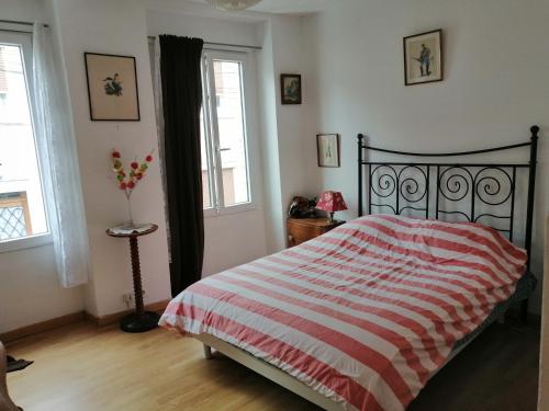 um quarto com uma cama com um cobertor listrado vermelho e branco em B1 Appartement en centre ville de Courtenay em Courtenay