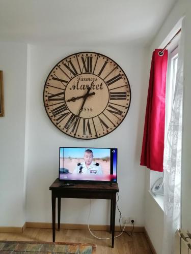 eine Uhr an der Wand über einem Fernseher auf einem Tisch in der Unterkunft B1 Appartement en centre ville de Courtenay in Courtenay