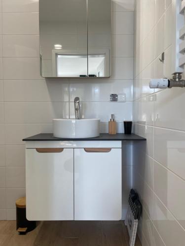 a white bathroom with a sink and a mirror at Complex Apartamenty - Po Schodkach in Koszalin