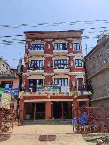 a large red brick building with a balcony at Hotel small town guest house in Bandīpur