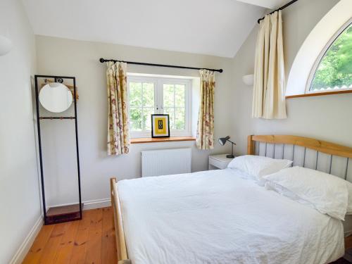 a bedroom with a bed and a window at Damson Tree Cottage in Bridport