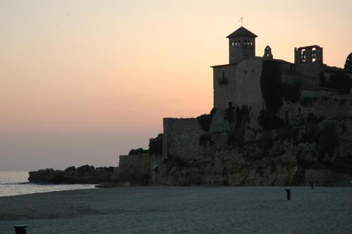 a castle on the beach with the sunset in the background at Altafulla Mar Hotel in Altafulla