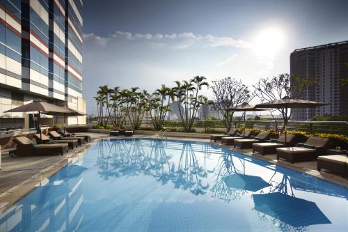 a swimming pool with lounge chairs and a building at Melia Hanoi in Hanoi