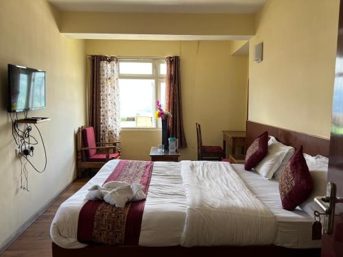 a hotel room with a large bed with a window at Khandroling Hotel in Gangtok