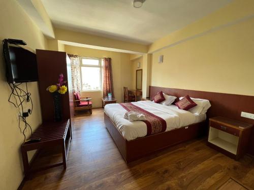 a hotel room with a bed and a television at Khandroling Hotel in Gangtok