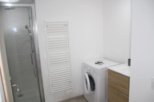 ein weißes Bad mit einer Waschmaschine und einer Dusche in der Unterkunft superbe appartement neuf lumineux in Badens