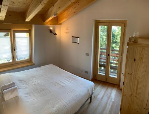 a bedroom with a large white bed and windows at Chalet Baita delle Favole di RosaRita in Berbenno di Valtellina