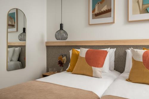 a bedroom with a bed with pillows and a mirror at BYPILLOW La Sal in Cádiz