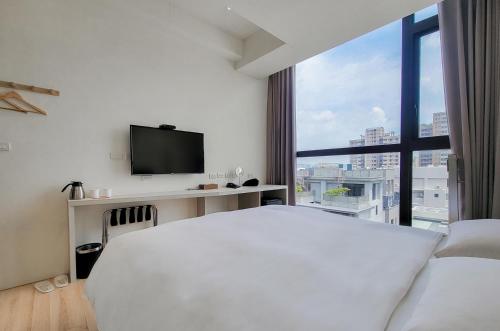 a bedroom with a white bed and a large window at CHECK inn Express Taichung Fuxing in Taichung