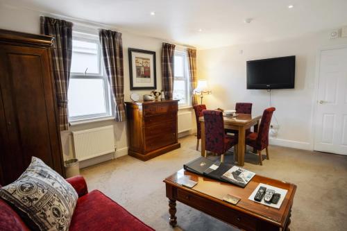 a living room with a table and a tv at The Town House in Douglas