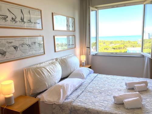 a bedroom with a white bed with a large window at Penthouse Bellavista in Lignano Sabbiadoro