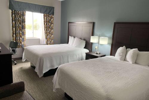 a hotel room with two beds and a window at Days Inn & Suites by Wyndham Cleburne TX in Cleburne