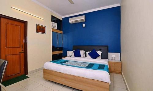 a bedroom with a large bed with blue walls at FabExpress Central Park in Dehradun