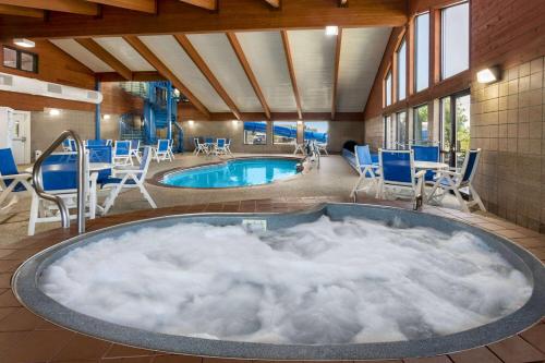 un jacuzzi en una habitación con sillas y una piscina en AmericInn by Wyndham Rapid City, en Rapid City