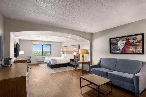 une chambre d'hôtel avec un lit et un canapé dans l'établissement AmericInn by Wyndham Rapid City, à Rapid City