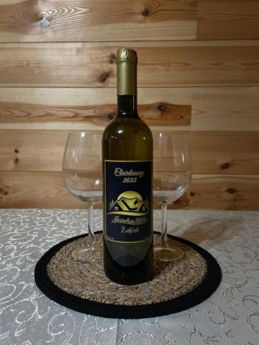 ジャブリャクにあるMountain Villas Žabljakのグラス2杯の横に置かれたワイン1本