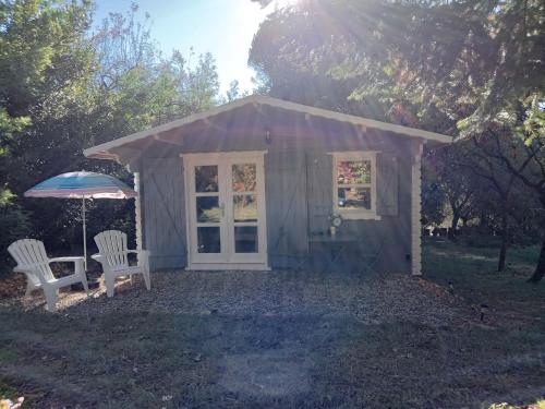 a small shed with two chairs and an umbrella at Chalet "Le Petit olivier" gîtes appart 'hôtel L'ÉCHAPPÉE BELLE D'AUBENAS Logement 2 sur 3 in Aubenas