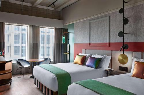 奧克蘭的住宿－QT Auckland，酒店客房配有两张床和一张书桌