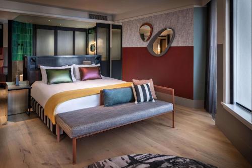 a bedroom with a large bed and a bench at QT Auckland in Auckland