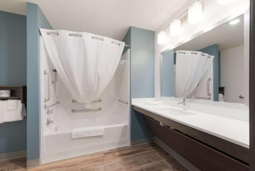 a bathroom with a sink and a shower with a mirror at WoodSpring Suites Philadelphia Northeast in Philadelphia