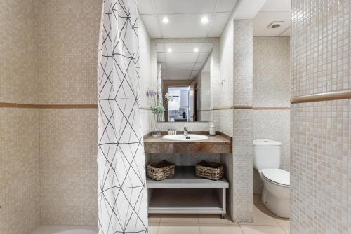 uma casa de banho com um lavatório, um WC e um espelho. em Lodging Apartments Liceu 11 em Barcelona