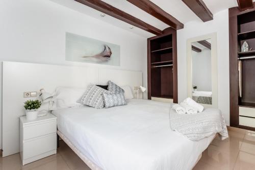 ein weißes Schlafzimmer mit einem großen weißen Bett und einem Spiegel in der Unterkunft Lodging Apartments Liceu 11 in Barcelona