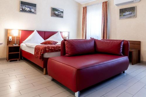 a hotel room with a red couch and a bed at Land-gut-Hotel am Ring in Meuspath