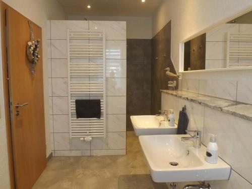 a white bathroom with two sinks and a mirror at Meiers FeWo in Tremmen