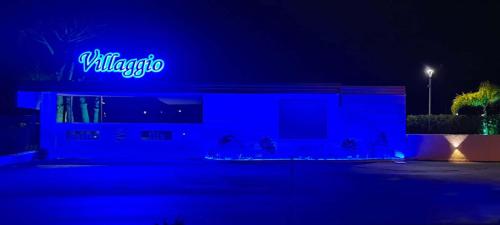 a building with a blue neon sign on it at Villaggio Jonio Blu in Bianco