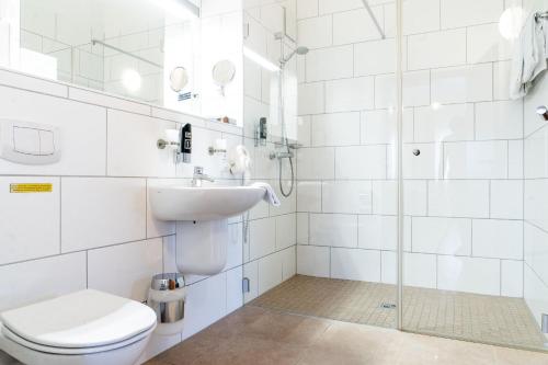 a bathroom with a toilet and a sink and a shower at Land-gut-Hotel am Ring in Meuspath