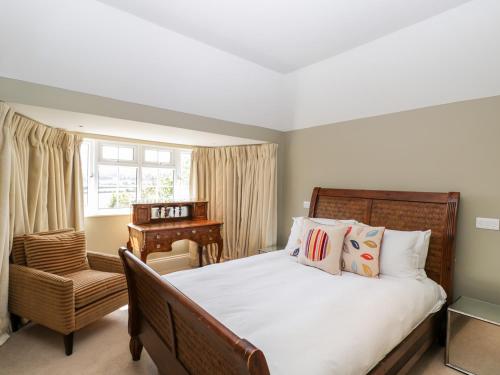 a bedroom with a bed and a chair and a piano at Gardeners Cottage in Hungerford