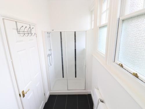 a white bathroom with a shower and a window at Magpies in Hollington