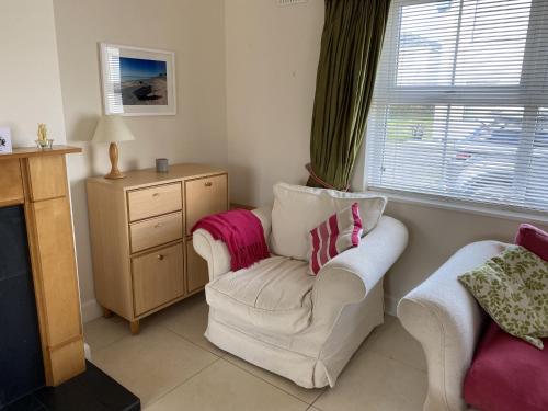 - un salon avec une chaise blanche et une commode dans l'établissement Castle Gardens Bungalow, Saint Helens Resort, Wexford - 3 Bedroom Sleeps 6, à Ballygerry