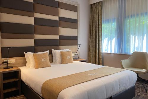 a bedroom with a large bed with a striped headboard at XO Hotels Blue Square in Amsterdam