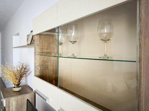 trois verres à vin sur une étagère dans une pièce dans l'établissement Aldo Apartment, à Tirana