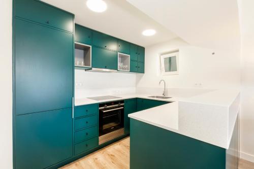 una cocina con armarios azules y encimeras blancas en Cascais Bay Terrace iii en Cascais