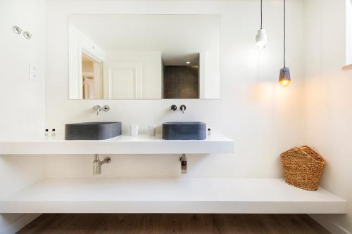 uma casa de banho branca com 2 lavatórios e um espelho em Cascais Bay Terrace iv em Cascais