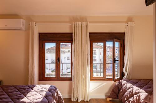 una camera da letto con un letto e due finestre con tende di Albergue El Encuentro a Villanueva de la Vera