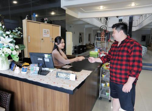a man and a woman standing at a cash register at Gading Guest House in Mataram