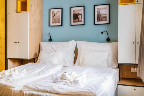 a bedroom with a white bed with three pictures on the wall at Zsóry Liget Camping & Resort in Mezőkövesd