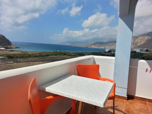a table and chairs on a balcony with a view of the ocean at Montemar Studios & Apartments in Arkasa