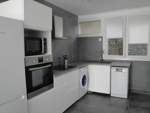une cuisine avec des armoires blanches et une laveuse et une sécheuse dans l'établissement T3 centre de Cassis parking, climatisé, wifi, à Cassis
