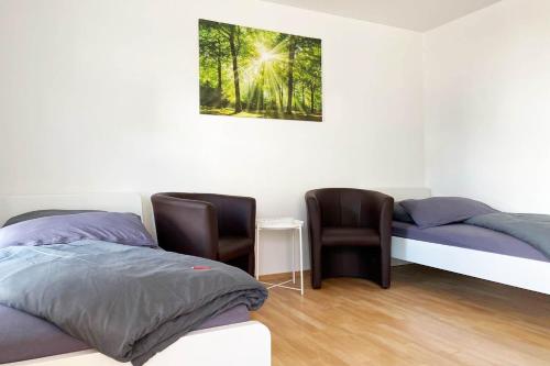 two beds in a room with two chairs and a picture on the wall at 1 Zimmer Apartment mit Balkon in Glauchau