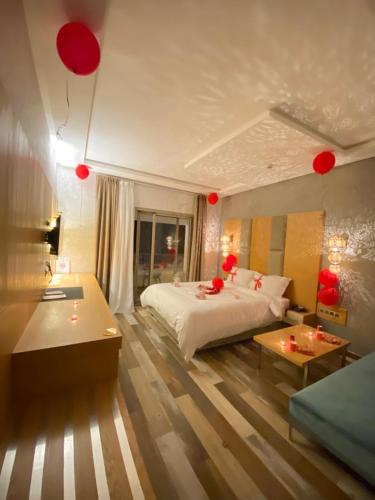 a bedroom with a bed and a table and red balloons at Hotel Atlantis Mazagan in Douar Draoud