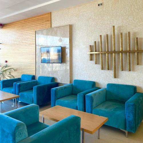 a waiting room with blue chairs and tables at Hotel Atlantis Mazagan in Douar Draoud
