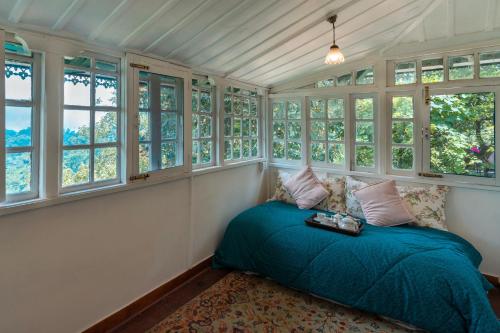 a bedroom with a bed in a room with windows at StayVista at Springfield with Scenic Lawn in Kasauli